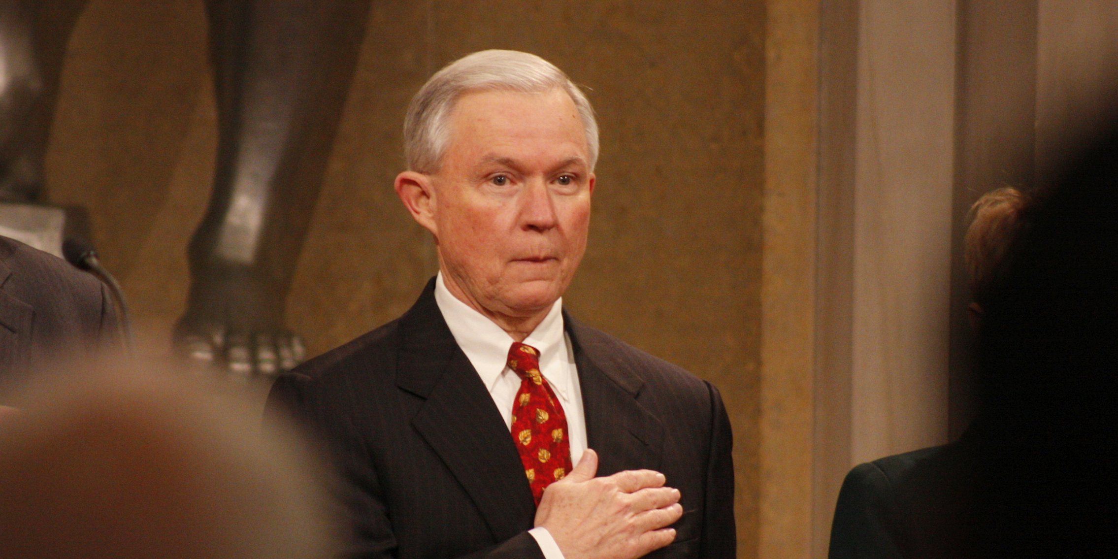 Attorney General Jeff Sessions holding his hand over his heart.