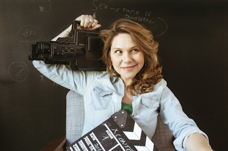 Erika Lust holds a camera and a clapperboard. 