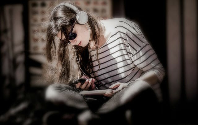 A woman listens to an audio recording through headphones.