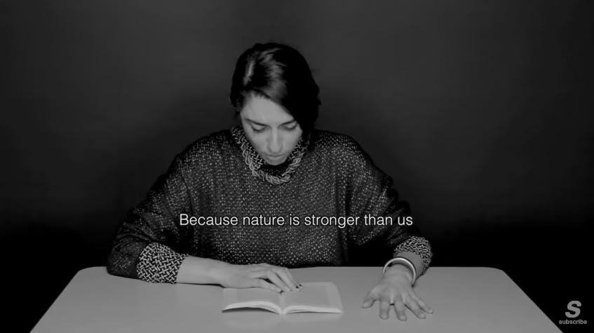 Image of a woman reading from a book with her hand gripped on the table. 