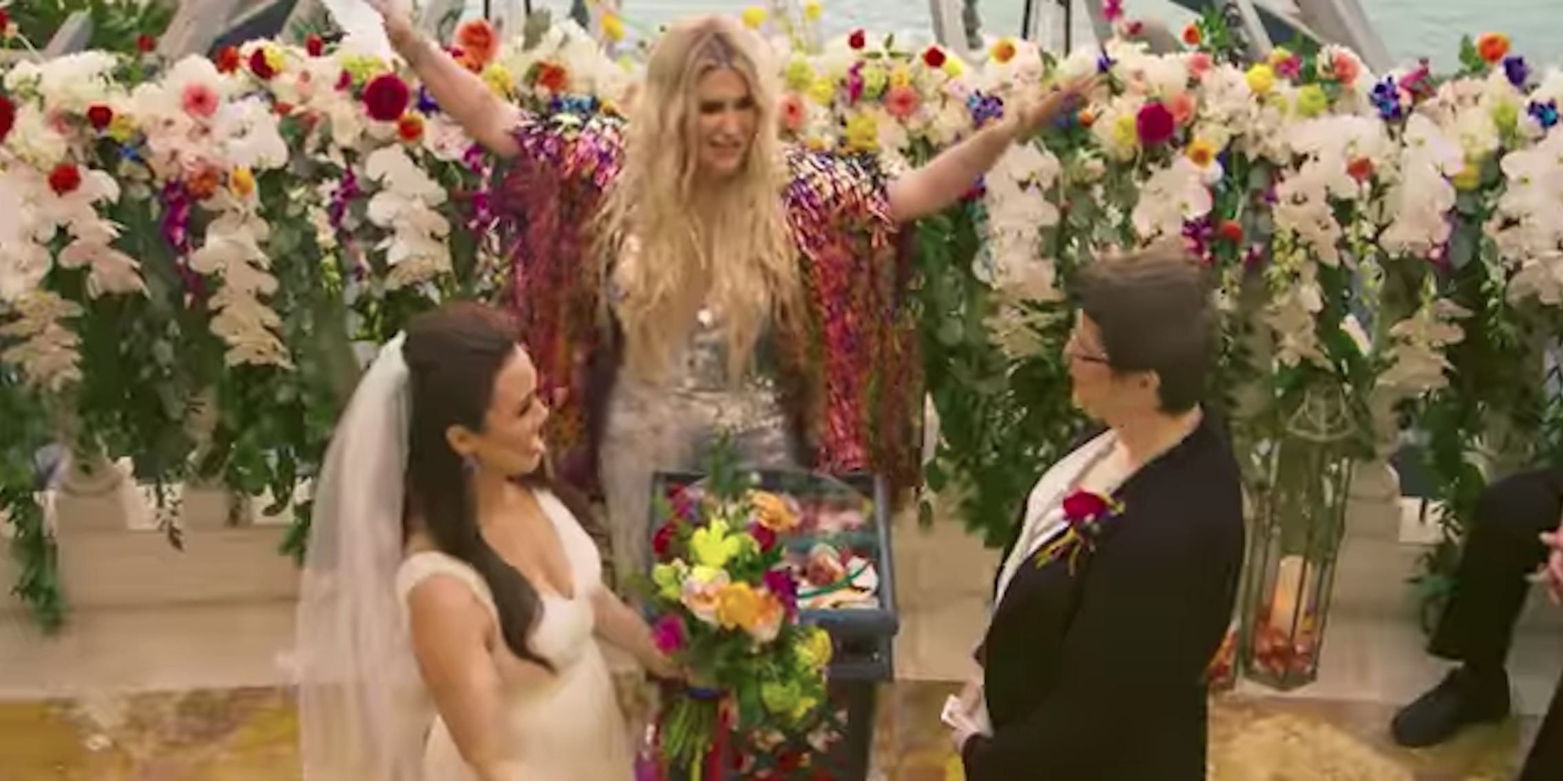 Kesha throws her hands up while officiating a wedding for two brides