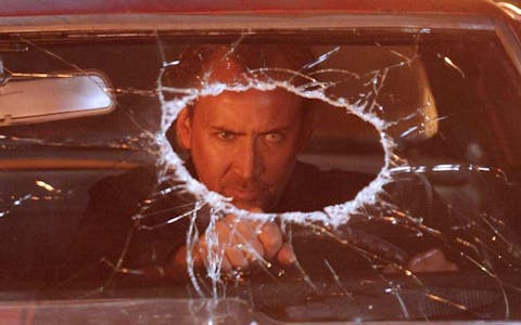 a scene from drive angry showing Nicholas Cage driving with a hole in his windscreen