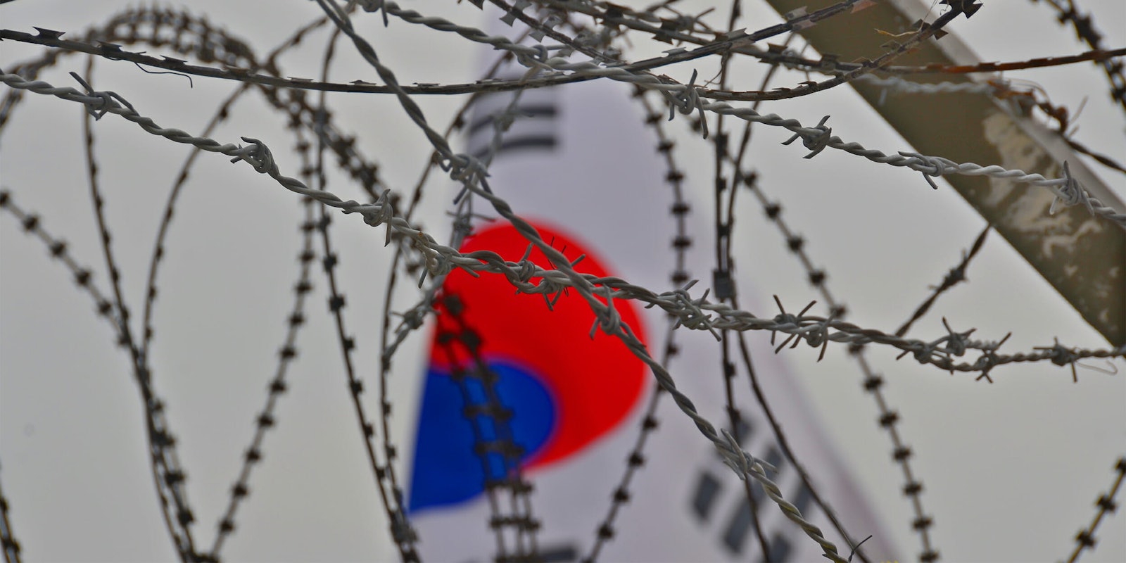 south korean flag behind barbed wire