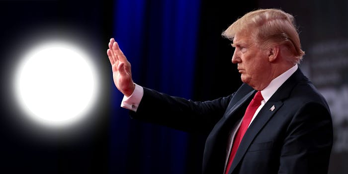 Trump reaching hand out near glowing orb floating in midair