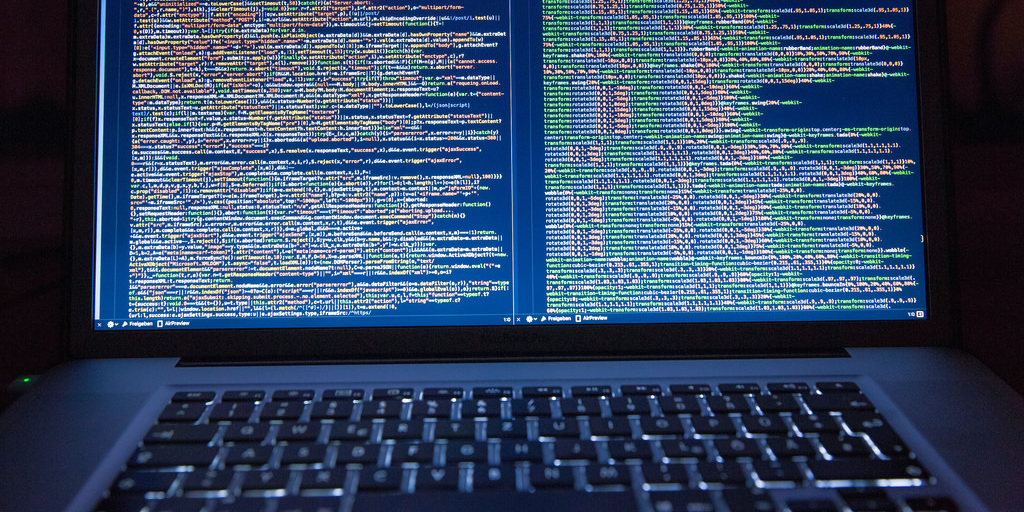 Laptop screen with code on it, illuminated keyboard