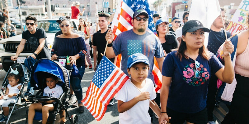 A family protesting the end of DACA, holding American flags.