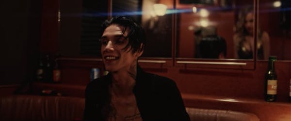 A man sits in a red bar in a scene from American Satan