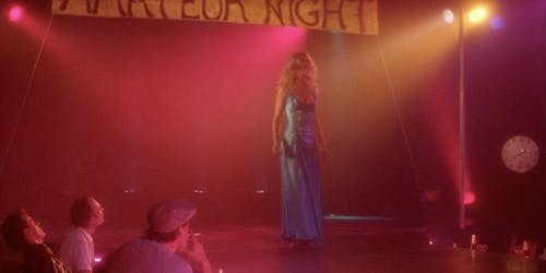 A woman stands on a stage in the movie Stripped to Kill