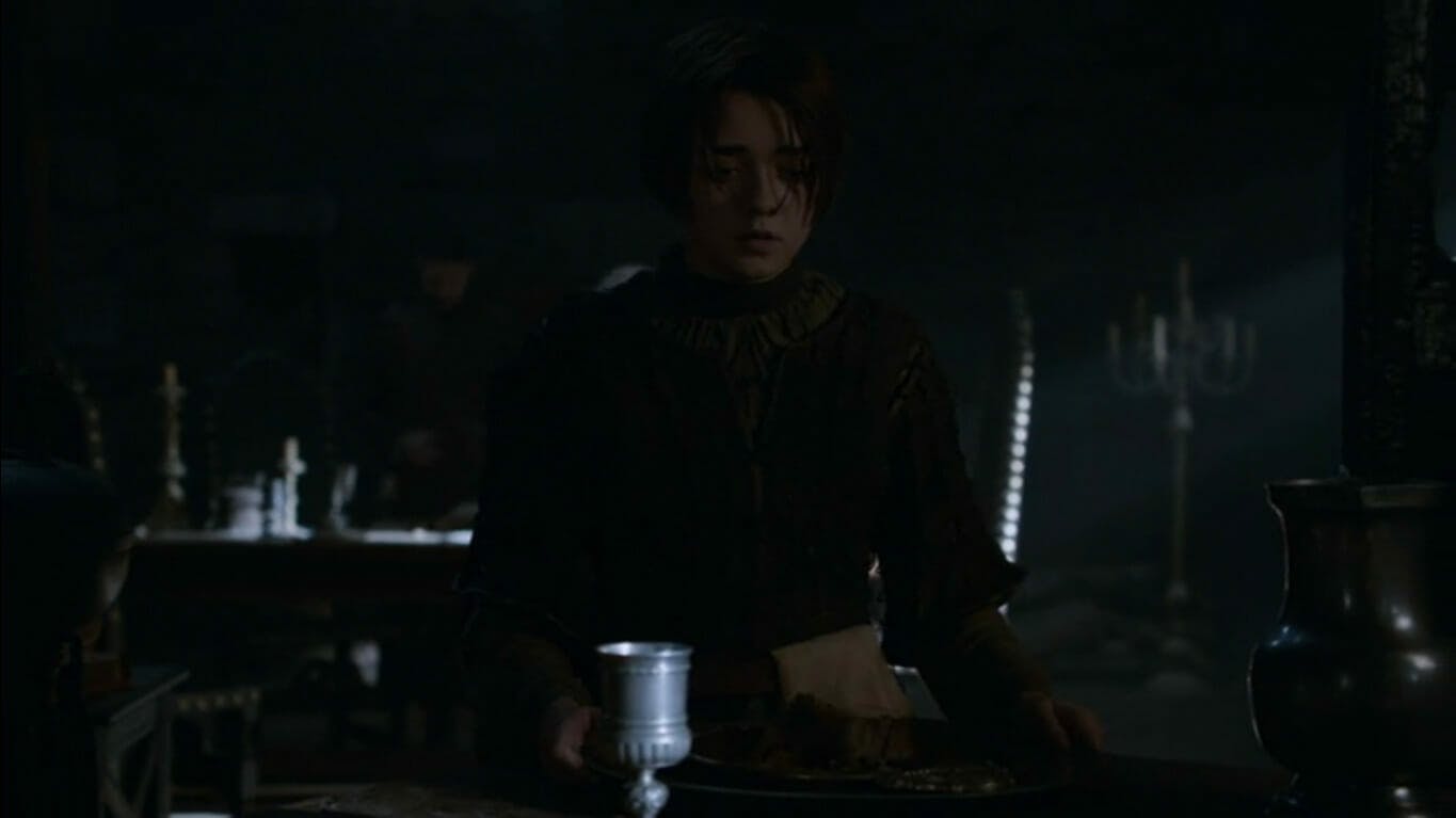 Image of Arya Stark sitting at a table in the dark