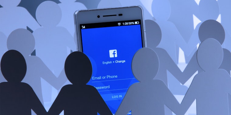 paper cutouts holding hands around a phone with the facebook app displayed