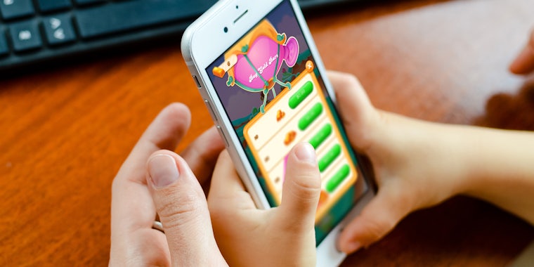 child using iphone to make in-app purchase while parent intervenes