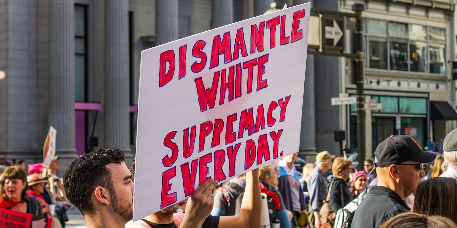 man holding 'dismantle white supremacy every day' sign