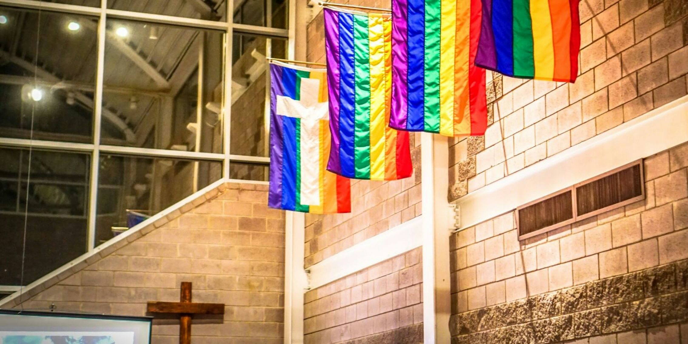 LGBTQ flags seen at a church in front of a Cross