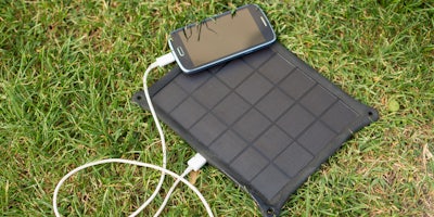 phone plugged into solar charger on grass