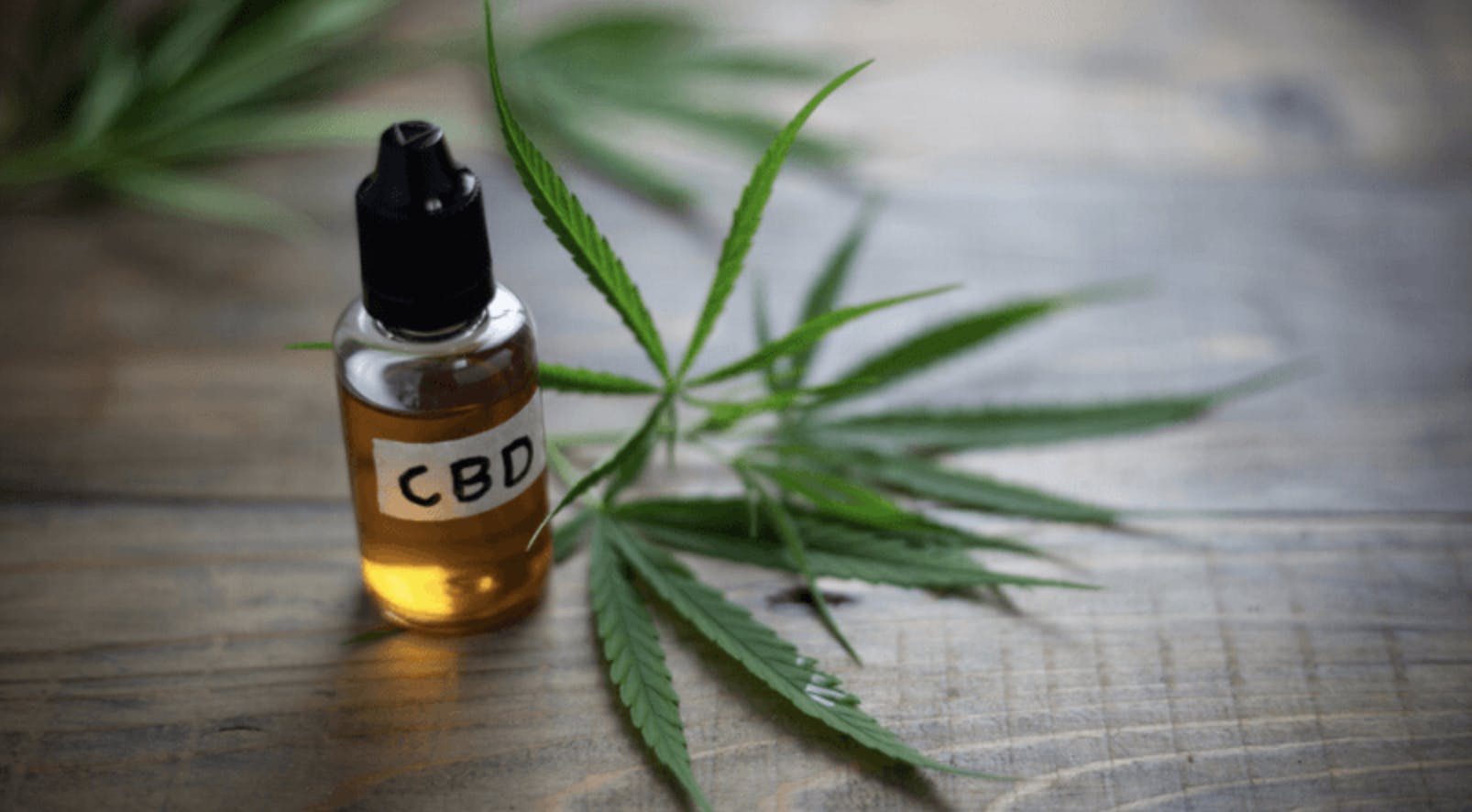 A bottle of CBD oil next to a cannabis leaf