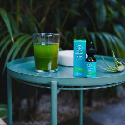 Select cbd oil on a blue table in a green outdoor space
