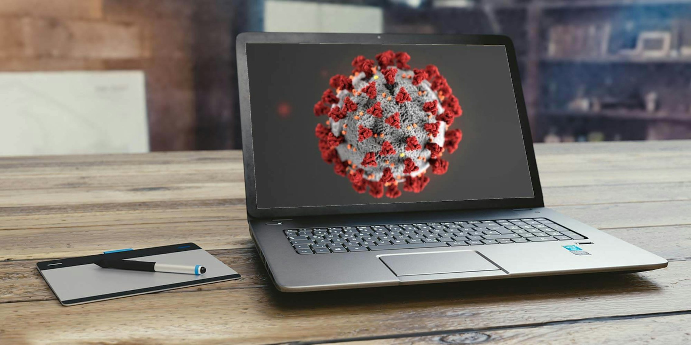 A laptop with an image of the coronavirus on its screen
