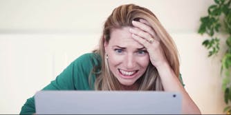 An upset woman staring at a laptop screen