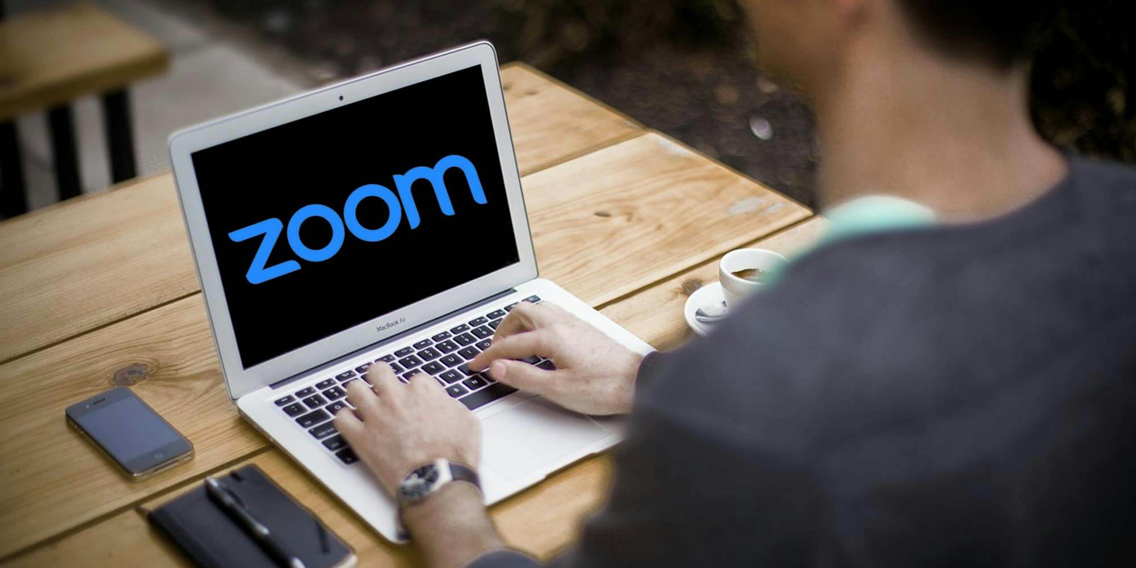 A man sitting in front of a laptop with the Zoom logo