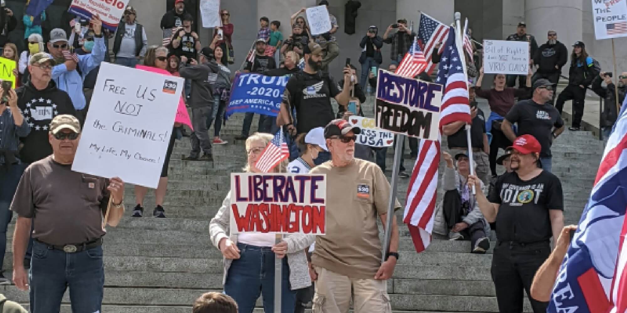 people holding signs for the reopen liberation movement