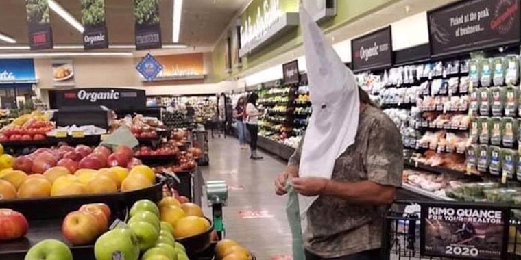 A man wearing a KKK hood while grocery shopping