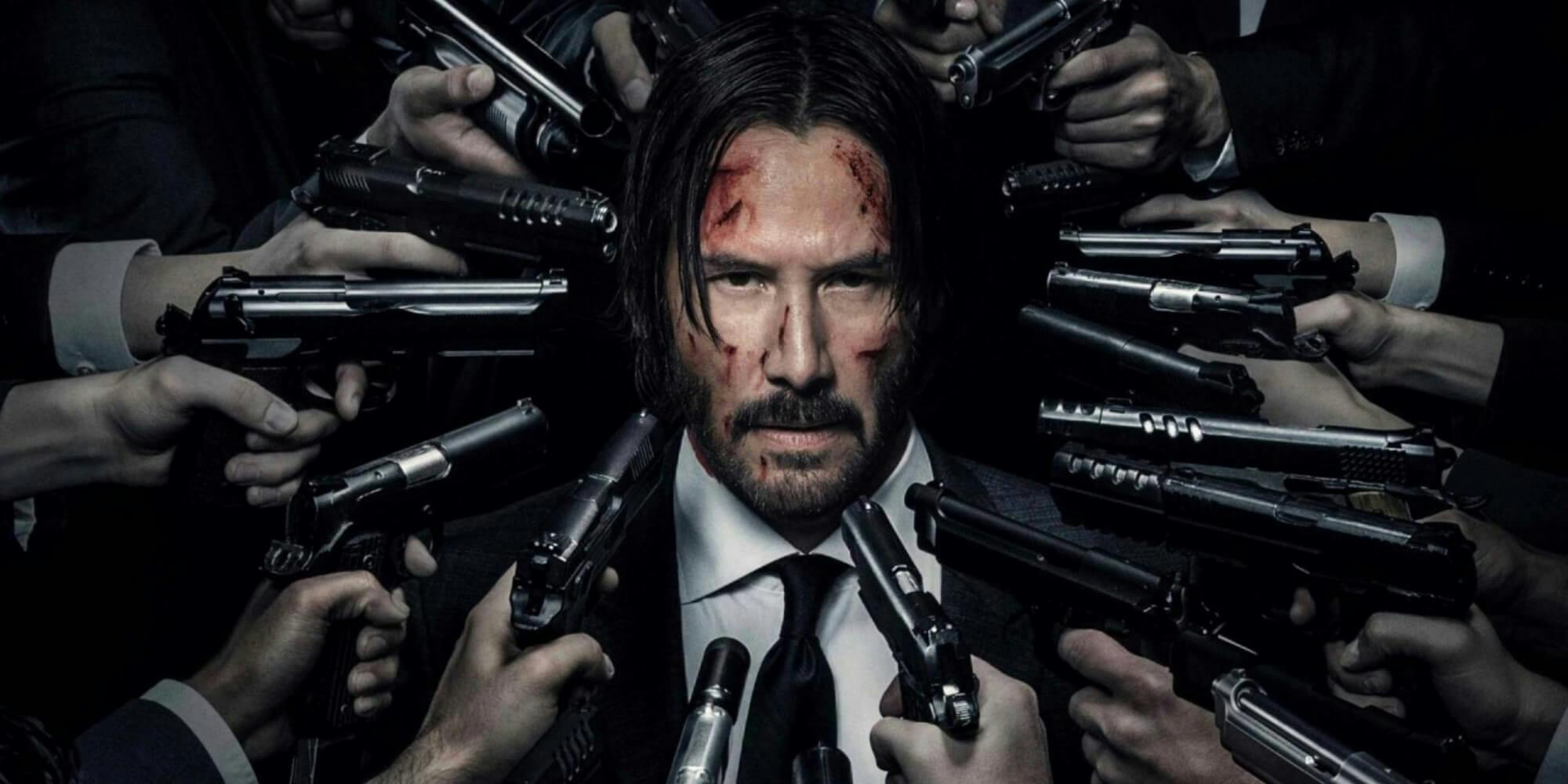 Photo of the movie John Wick where Keanu Reeves is surrounded by bad guys pointing guns at his face.