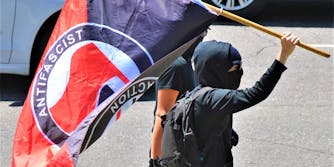 person carrying Antifascist Action flag