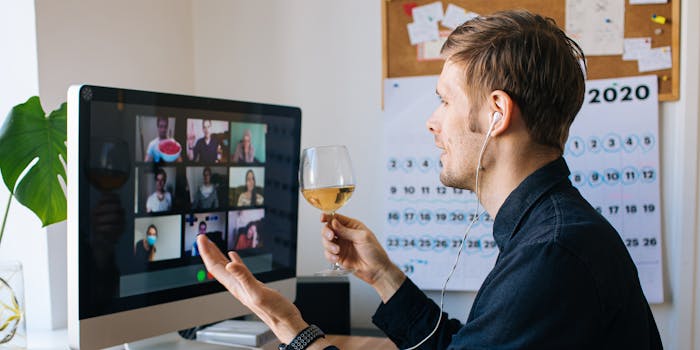 man holding glass of wine on zoom call