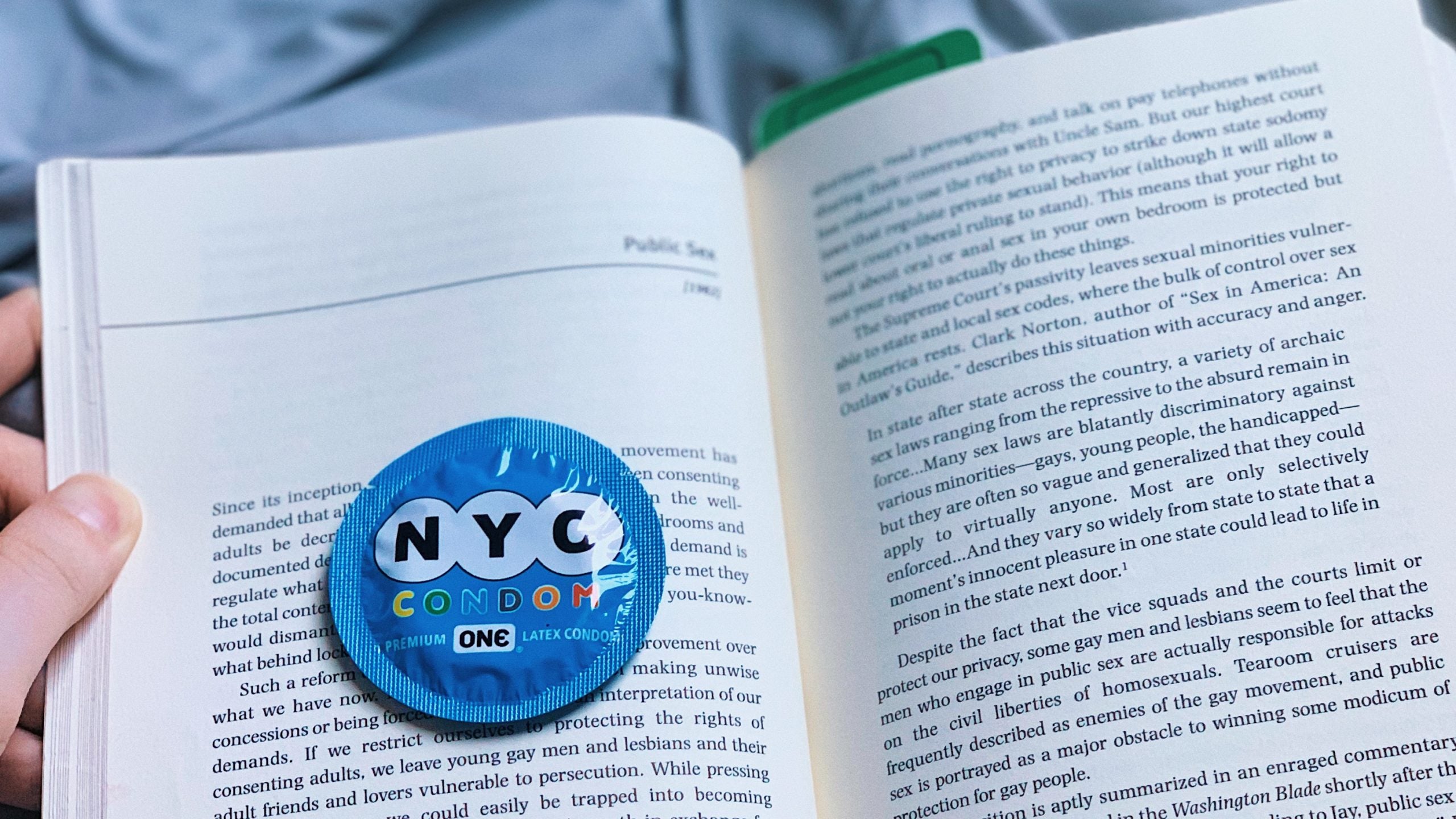 A closeup of a condom on top of Pat Califia's essay "Public Sex."