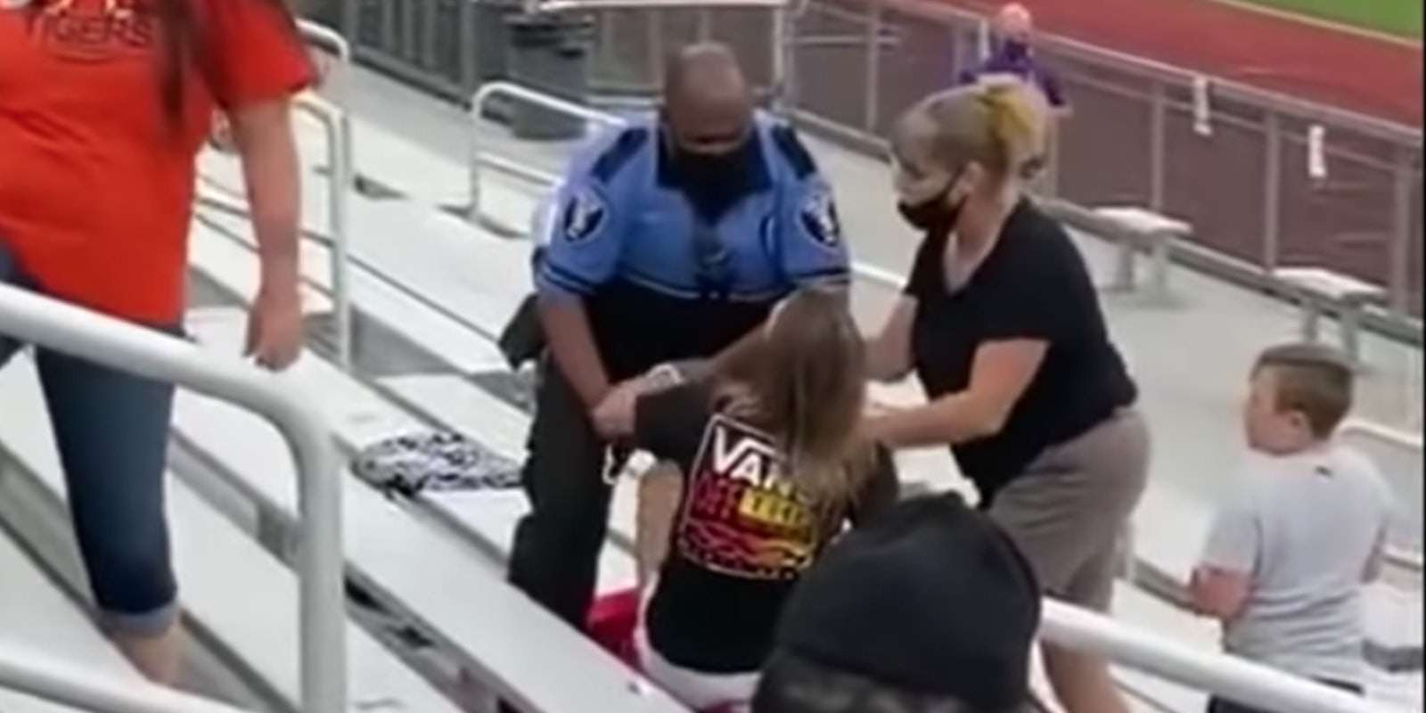 A police officer arresting a woman for not wearing a mask