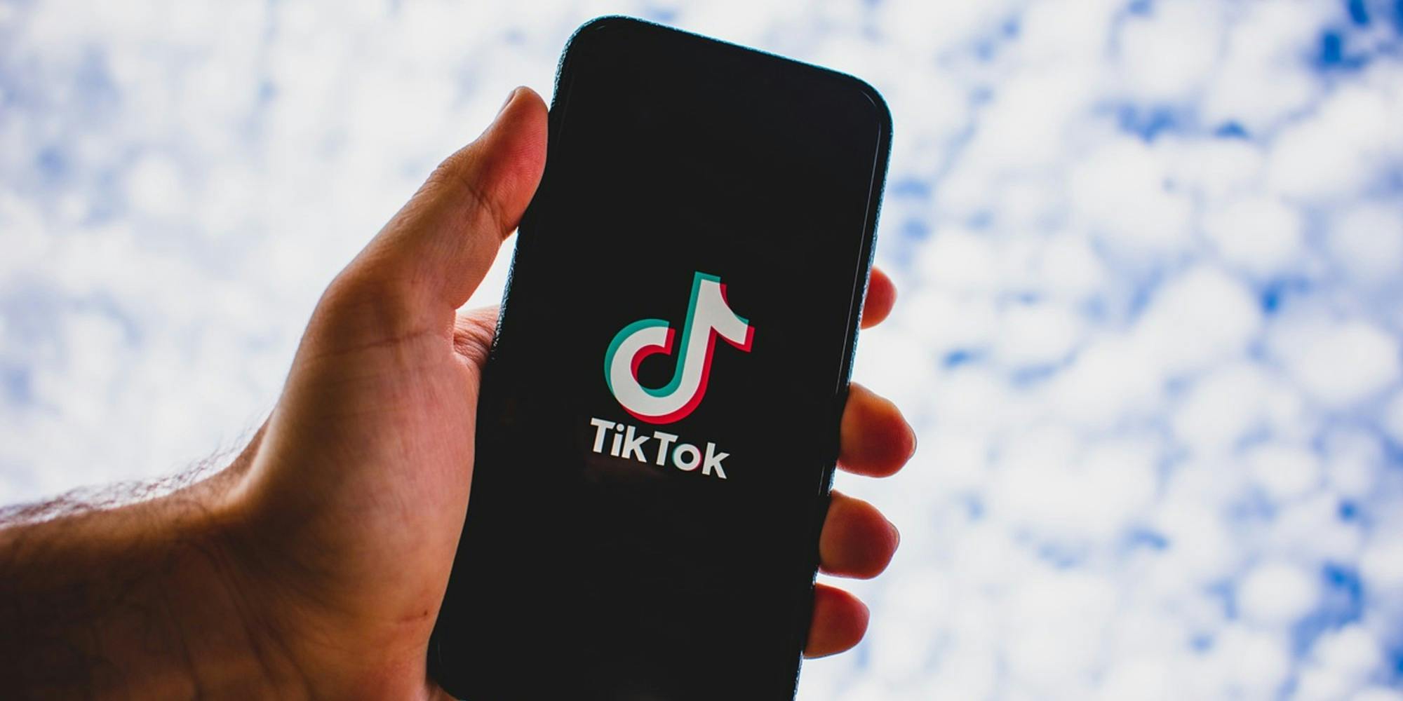 A person holding a phone with the TikTok app