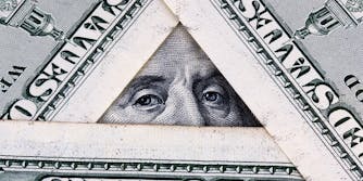 hundred dollar bills arranged in a triangle, showing benjamin franklin's eyes