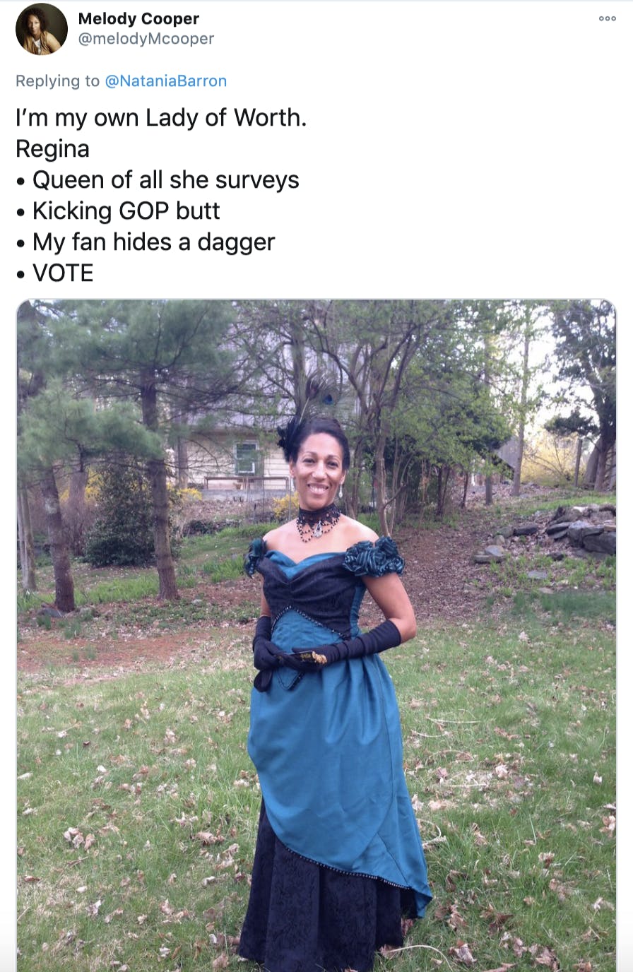 'I’m my own Lady of Worth. Regina • Queen of all she surveys • Kicking GOP butt • My fan hides a dagger • VOTE' picture of a Black woman with her hair pinned up, wearing a blue and black historic evening gown