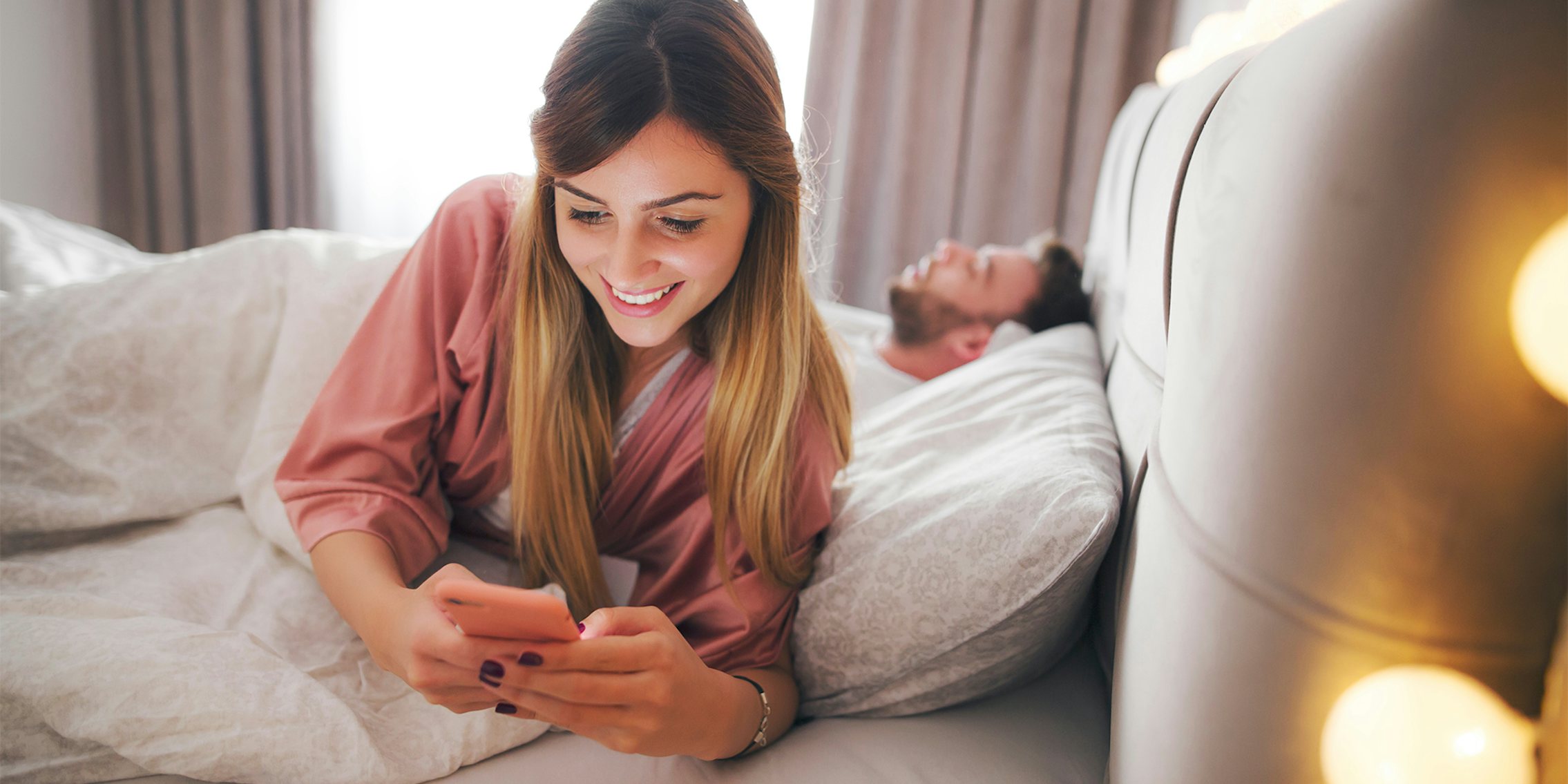 woman about to wake her sleeping partner after seeing her phone