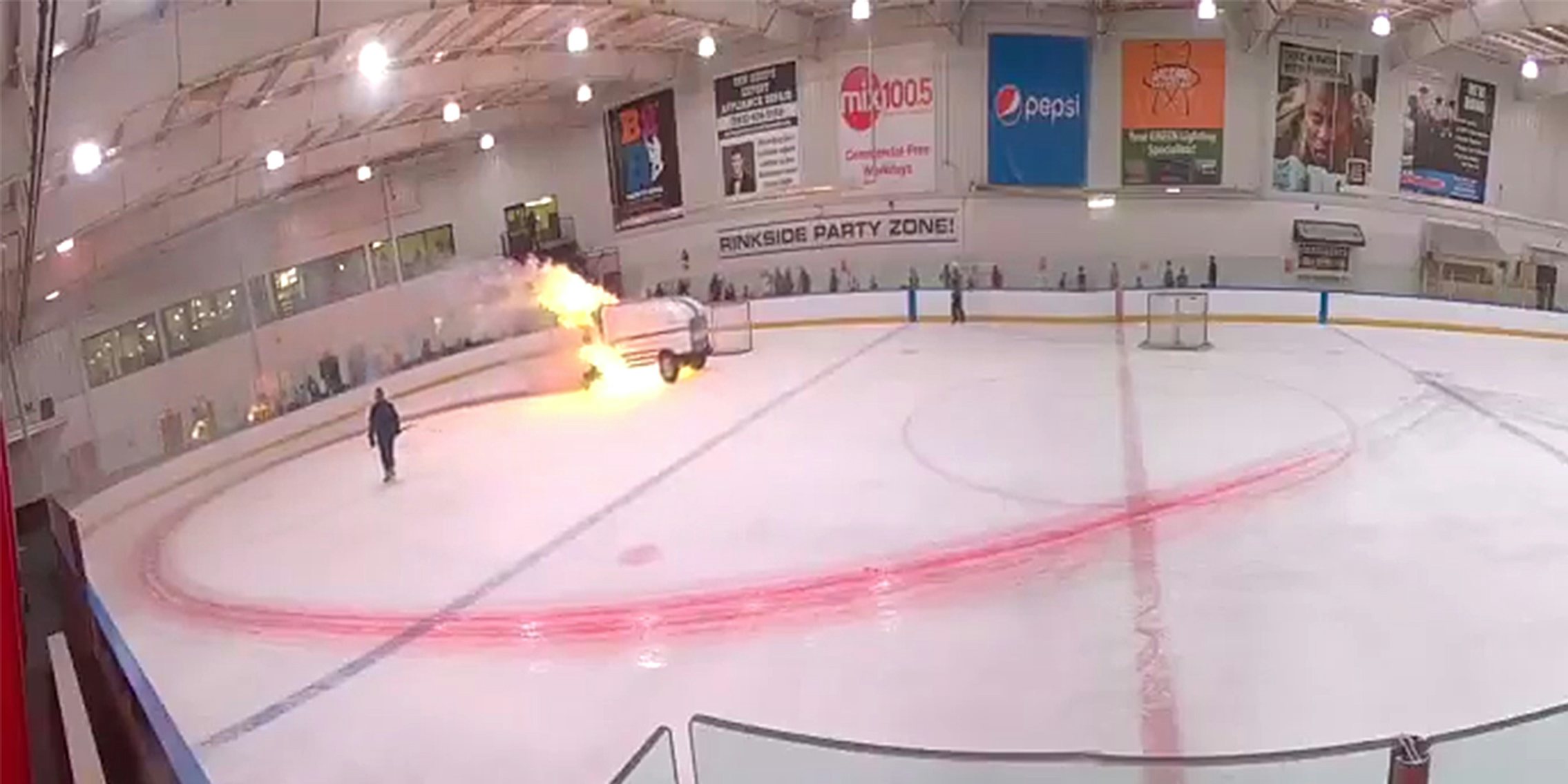 zamboni on fire in the center of a hockey rink