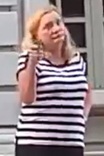 woman in striped shirt pointing a pistol with one hand on her hip