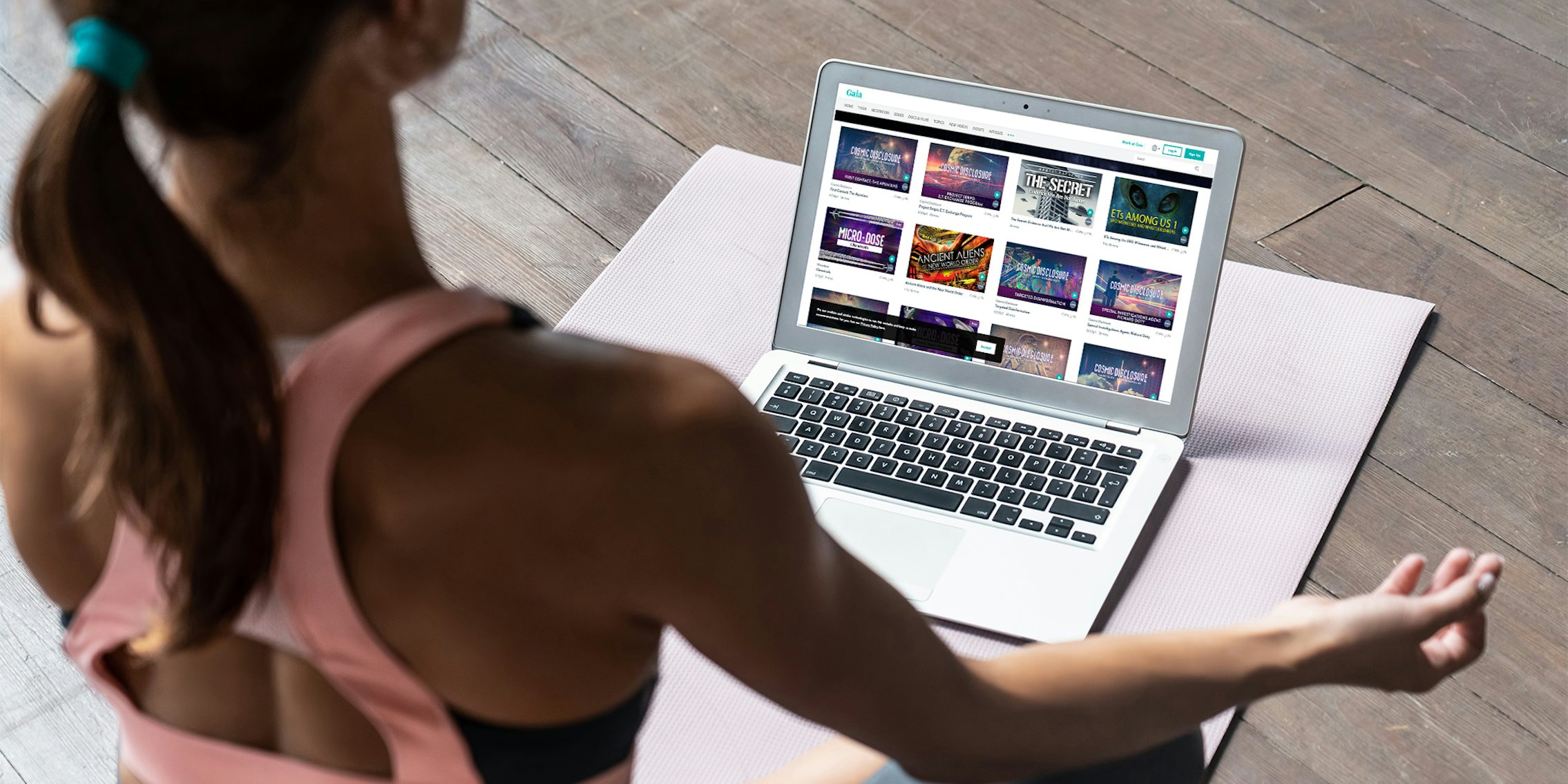 woman in yoga pose watching conspiracy videos on laptop