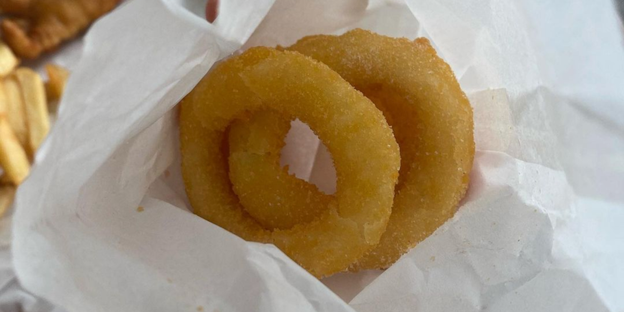 Two pale onion rings laid on crinkled white paper
