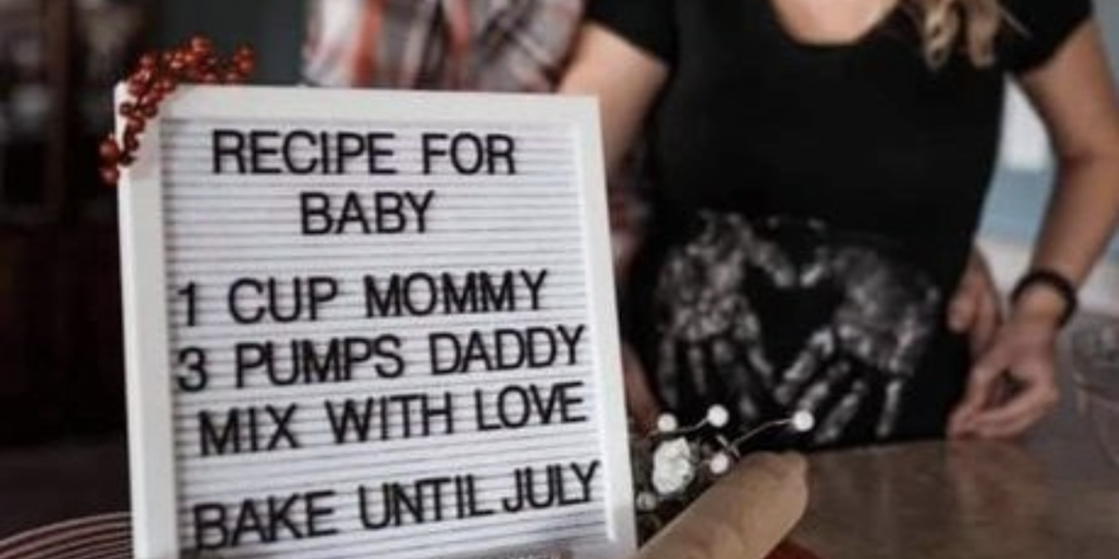 'imagine using your baby announcement to tell the world your husband is bad at sex' a white couple kissing in soft focus behind a sign that says 'Recipe For Baby. 1 Cup Mommy. 3 Pumps Daddy. Mix With Love. Bake Until July.'