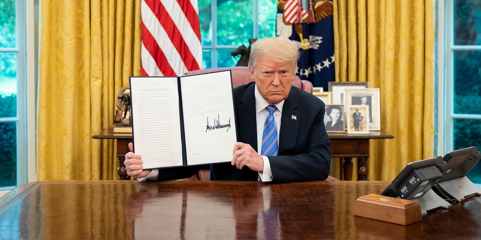 President Donald Trump in the Oval Office with a signed Executive Order