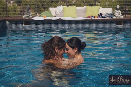 two female performers share a kiss in the pool