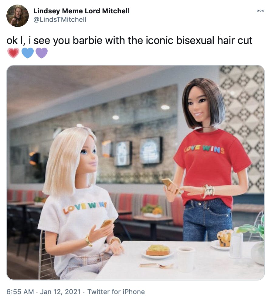 Barbie is sat at a white table wearing her white love wins shirt. The girlfriend doll, in a red love wins shirt, approaches the table tapping her phone.