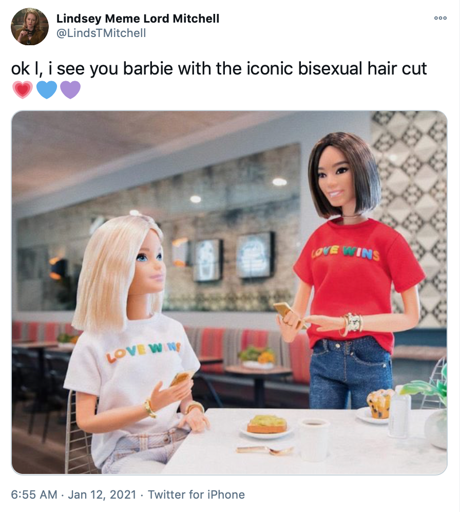 Barbie is sat at a white table wearing her white love wins shirt. The girlfriend doll, in a red love wins shirt, approaches the table tapping her phone.