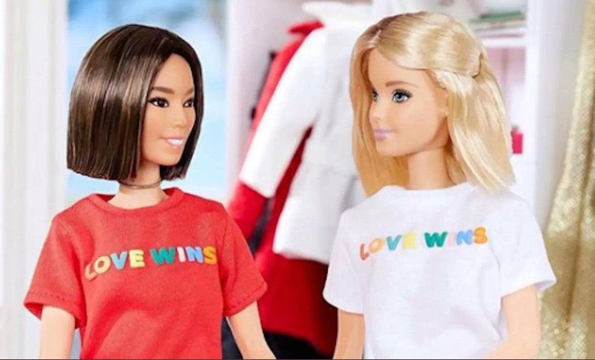 An Asian doll with a brown bob wearing a red love wins t-shirt sits across from Barbie who is wearing a matching white t shirt
