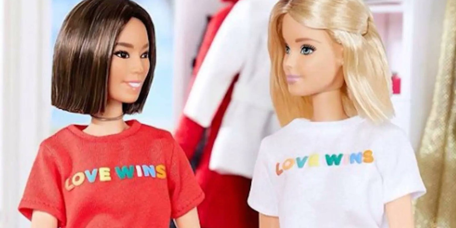 An Asian doll with a brown bob wearing a red love wins t-shirt sits across from Barbie who is wearing a matching white t shirt