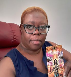 Image of Ms. Adriene (A.D) Joyce holding a tarot card.
