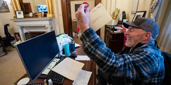 "Bigo" Barnett holds a piece of Nancy Pelosi's mail in the air, laughing as he sits at her desk