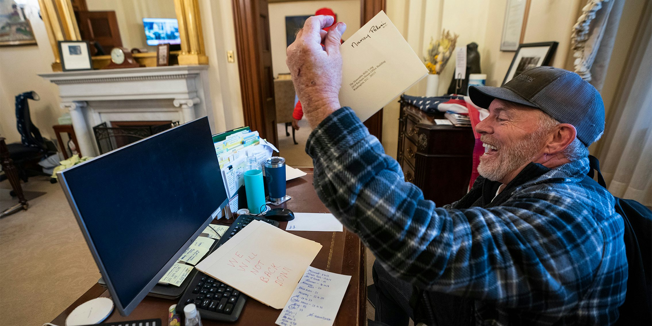 'Bigo' Barnett holds a piece of Nancy Pelosi's mail in the air, laughing as he sits at her desk
