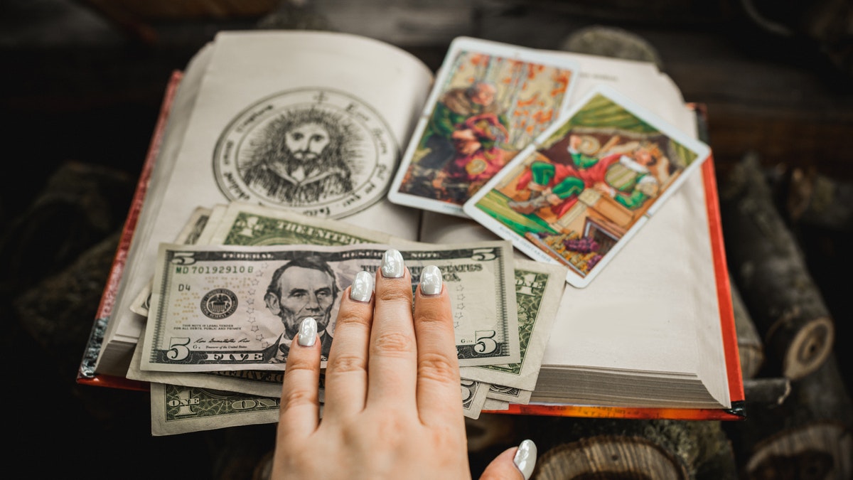 A hand reaches out to pay for a tarot card reading