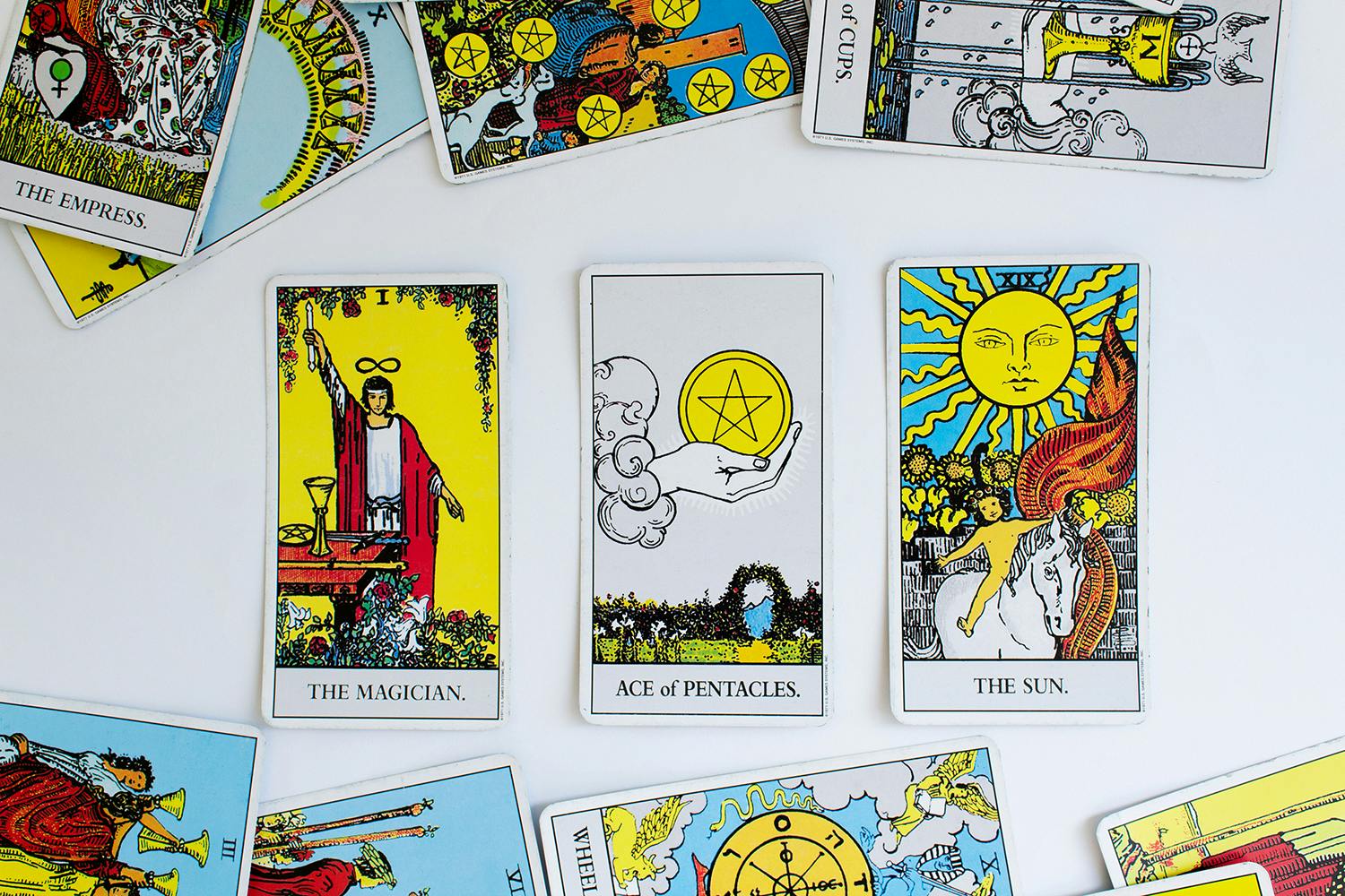 Photo of the Rider-Waite tarot deck spread out, with the magician, ace of pentacles, and the sun facing out.